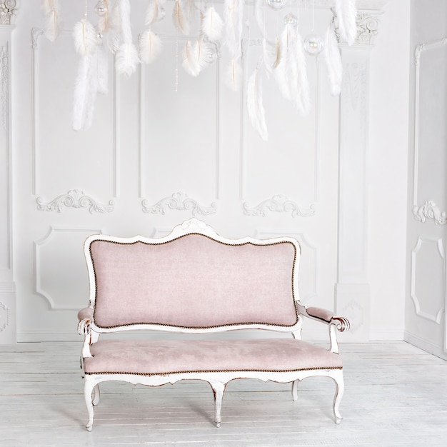 Классический белый интерьер с розовым диваном.