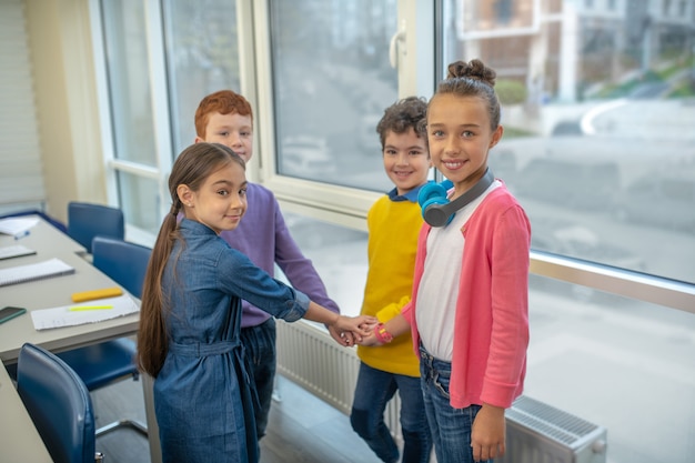 Classmates holding their hands in the classroom