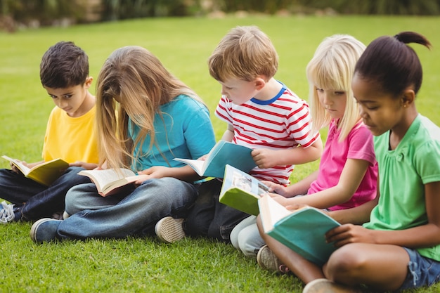 Classmates sitting in grass and reading books