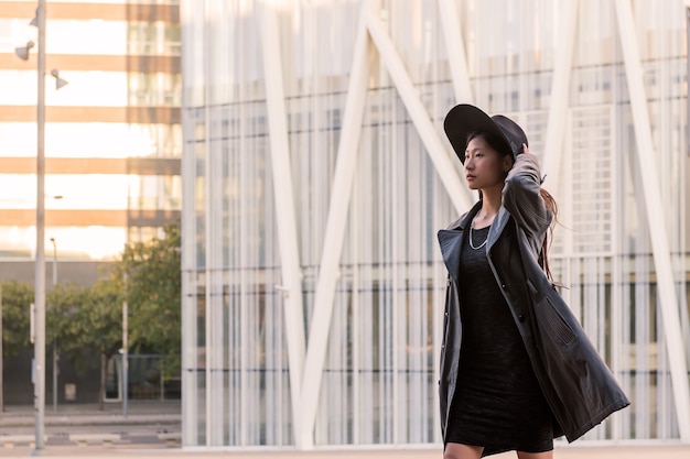 Classy asian woman in hat walking by the city