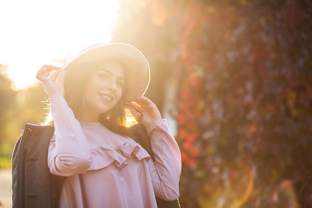 Foto elegante donna sorridente con il trucco naturale che indossa un cappello, godendosi il caldo clima autunnale. spazio per il testo