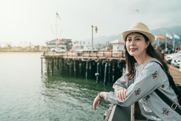 想象一个优雅的女人倚在码头的护栏上，带着平静的微笑看着别的地方。