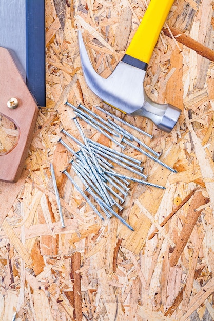 Claw hammer handsaw and nails on plywood