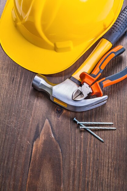 Claw hammer nippers nails yellow helmet on vintage wooden board construction concept