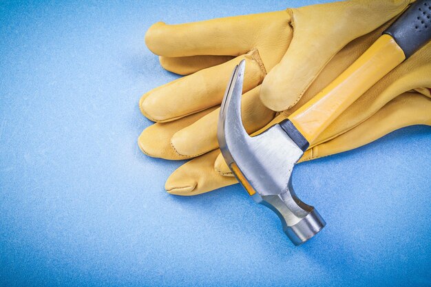 Claw hammer safety gloves on blue background construction concept