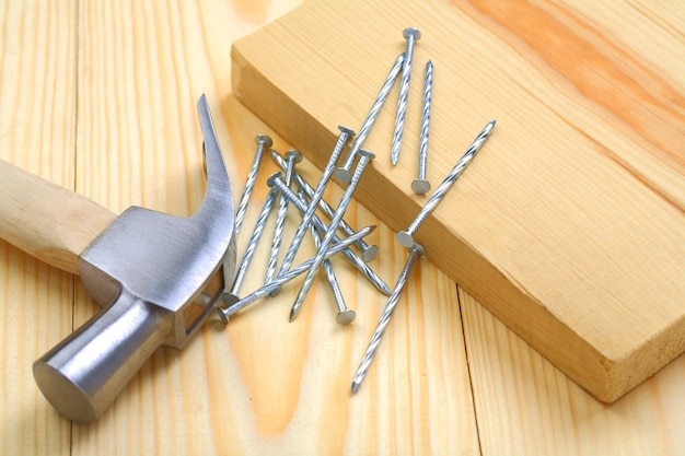 Claw hammer with nails and timber on table