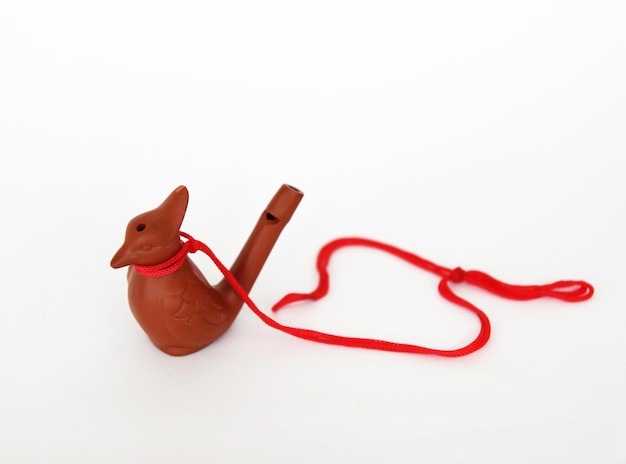 Clay bird whistle with red lace on white background