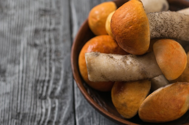 Clay bowl filled with fresh aspen on a wooden table. Natural food from the forest.