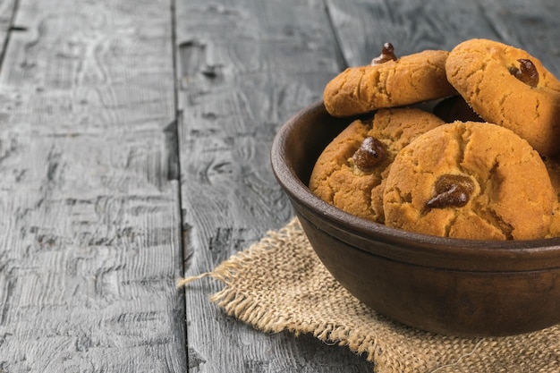 A clay bowl with homemade cookies on a wooden table