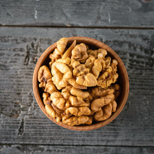 Clay bowl with the kernels of walnuts on the black wooden table