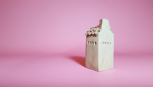 Модель глиняного дома на розовом фоне