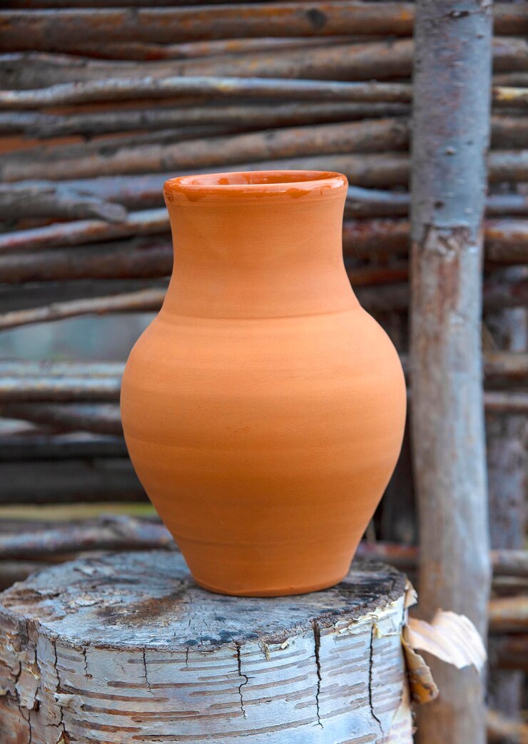 Photo clay jug on a stump and a wooden fence