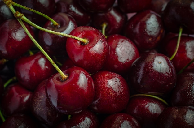 Clay plate with ripe red cherries on a wooden old table.