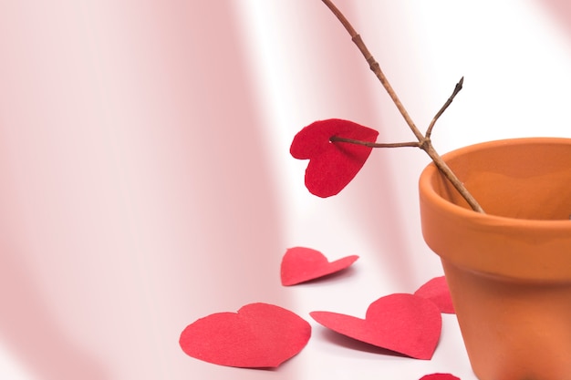 clay pot with tree branch and red hearts around the pot