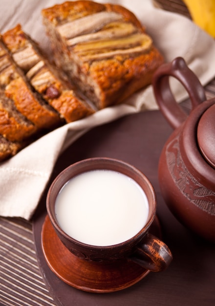 Clay theekop, theepot en bananenbrood op oude houten tafel