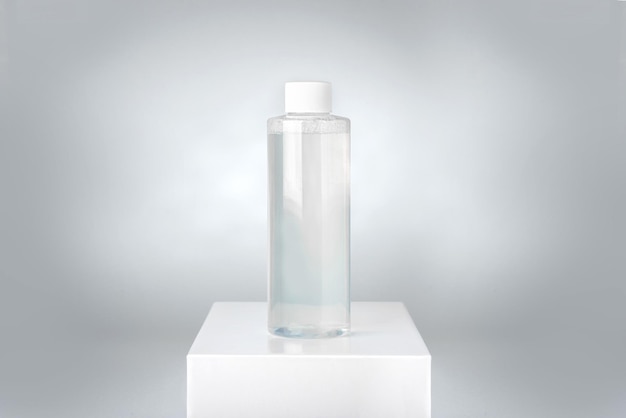 Clean bottle of micellar water on white pedestal