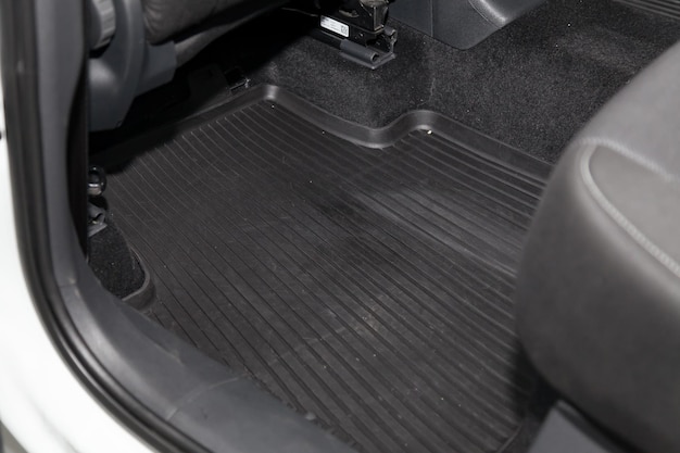 Clean car floor mats of black rubber under rear passenger seat in the workshop for the detailing vehicle dry cleaning Auto service industry Interior of sedan