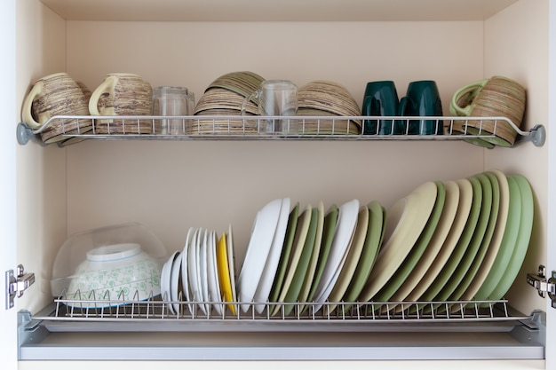 Clean dishes in white and green tones in  drying cabinet.