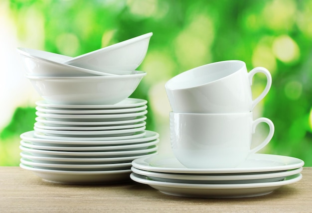 Clean dishes on wooden table on green background