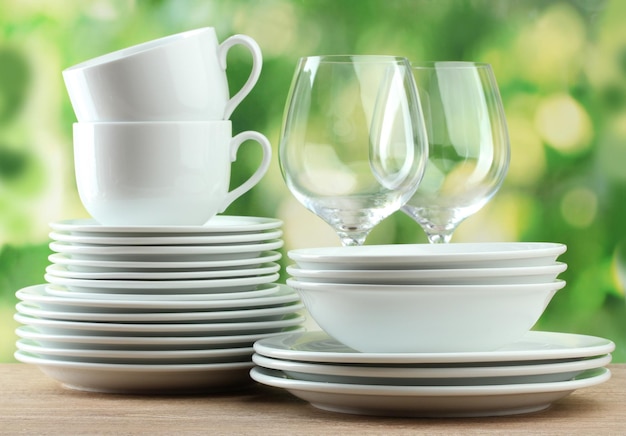 Clean dishes on wooden table on green background