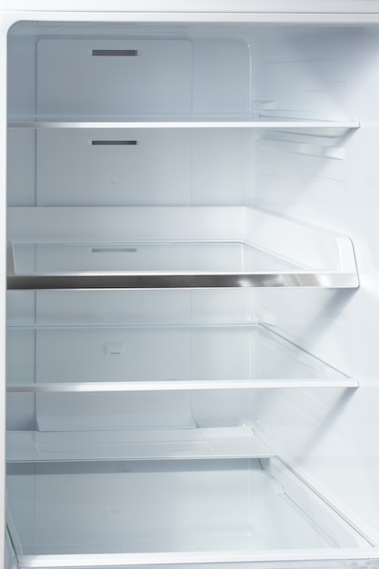 Clean empty shelves in white refrigerator.