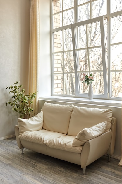 Чистый семейный номер с белым кожаным диваном и большим окном