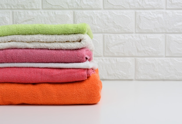 Clean folded terry towels on white shelf, bathroom interior