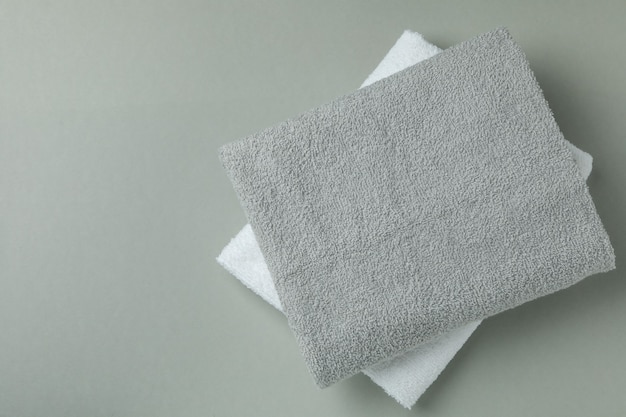 Clean folded towels on gray background, space for text