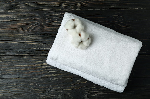 Clean folded towels with cotton on wooden background, top view