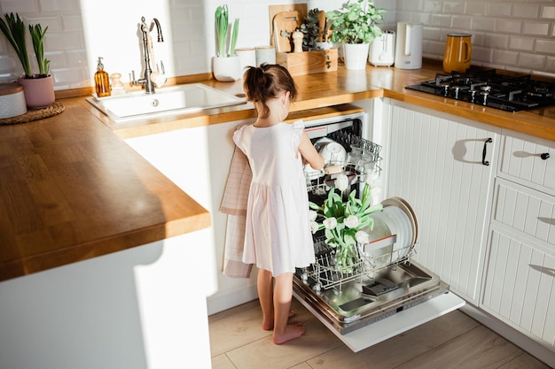 Концепция чистой кухни Цветы белых тюльпанов стоят в посудомоечной машине