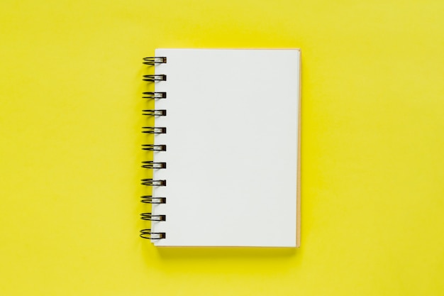 目標と解決のためのきれいなメモ帳。あなたのデザインのモックアップ。黄色の背景にスパイラルメモ帳。