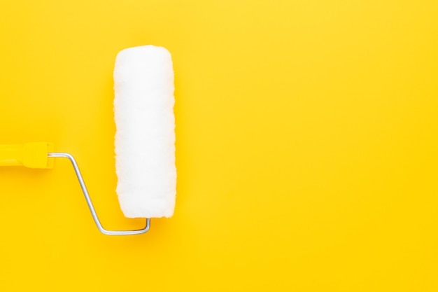 Clean paint roller with yellow handle on the yellow background with copy space