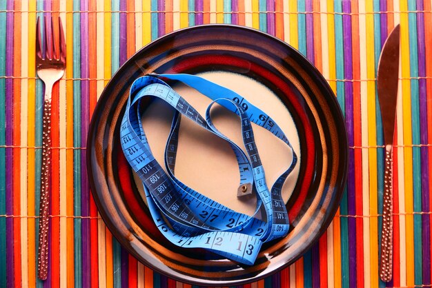 Clean plate with measurement tape and cutlery on table cloth