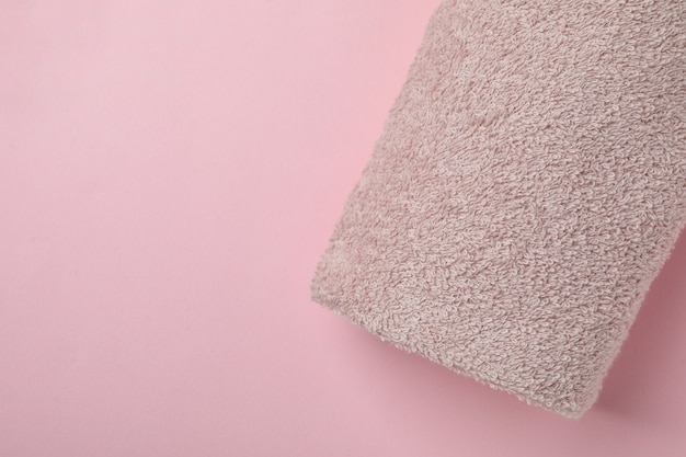 Clean rolled towel on pink background, space for text