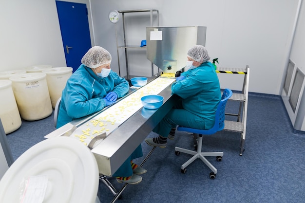 Foto clean room due donne lavorano in linea con le pillole