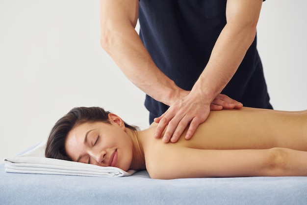 Clean skin Young woman is lying down when man doing massage of her body at spa