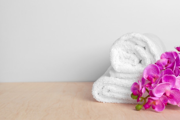 Clean soft towels with flower on wooden table