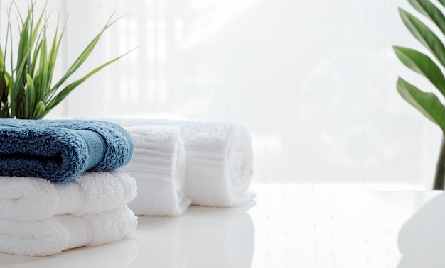 Clean towels and houseplant on white table.