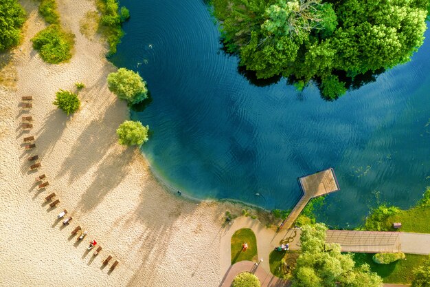Clean warm sandy beach next to the river and green shore. Blue water, drone view.