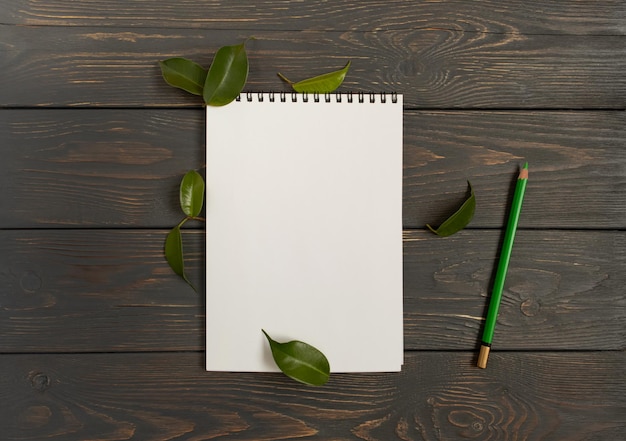 A clean white notebook page with a pencil on a dark wooden background Space for text