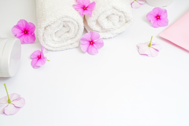 Clean white rolled towels with flowers on white copy space for text frame