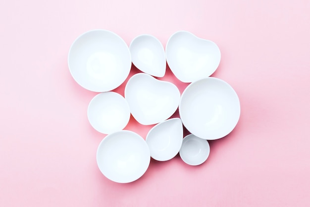 Clean white tableware on pink background. Top view