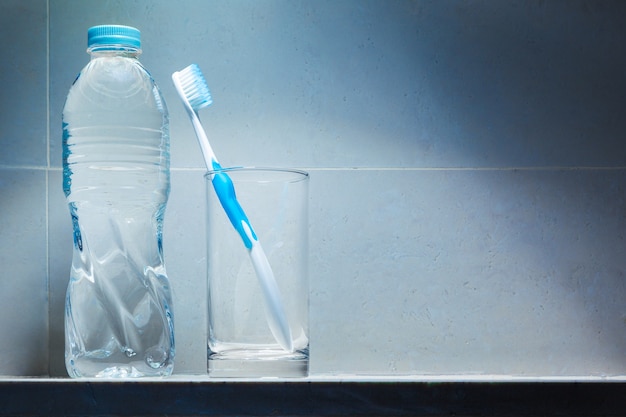 Clean white toothbrush with blue trim in clear drinking glass 