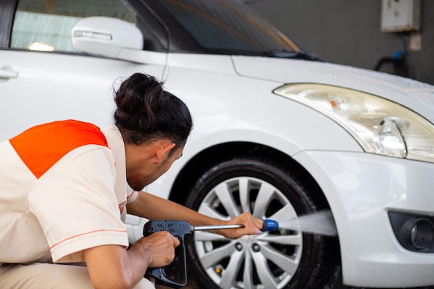 Foto adulto per il servizio di auto più pulito con uniforme per il veicolo pulito al cliente. la cura dell'auto del lavoratore intelligente prepara l'attrezzatura per la polvere dell'aspirapolvere.