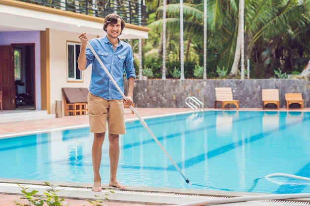 Cleaner of the swimming pool . Man in a blue shirt with cleaning equipment for swimming pools, sunny