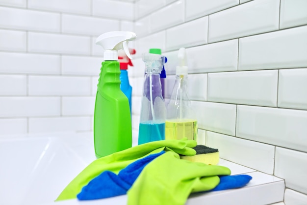 Cleaning in bathroom, hygiene, cleanliness in house. Detergents rag gloves on the background of white tiled wall, copy space