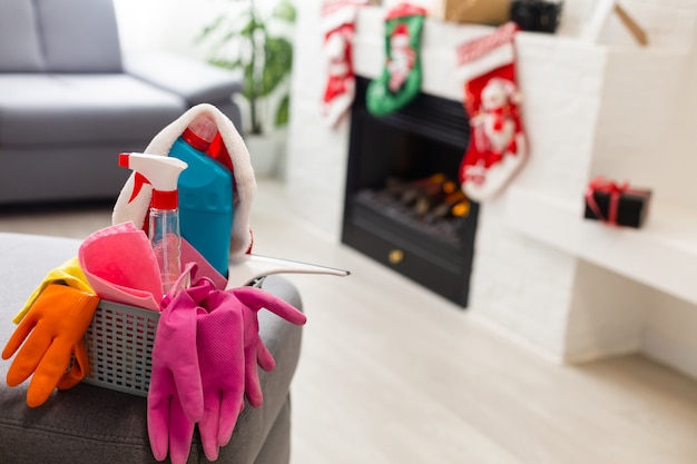 Cleaning before Christmas. Multicolored cleaning supplies. Sponges, rags and spray with festive decorations against modern home background