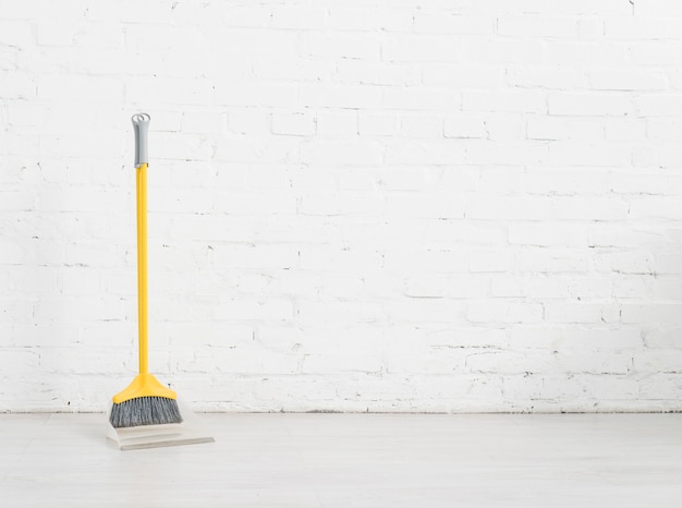 Cleaning broom with white brick wall