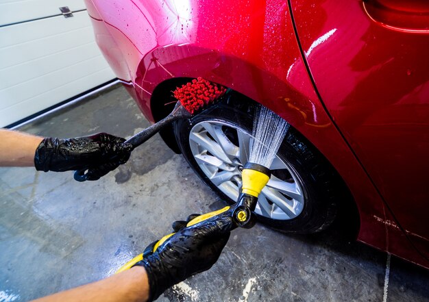 Cleaning the car wheel with a brush and water.