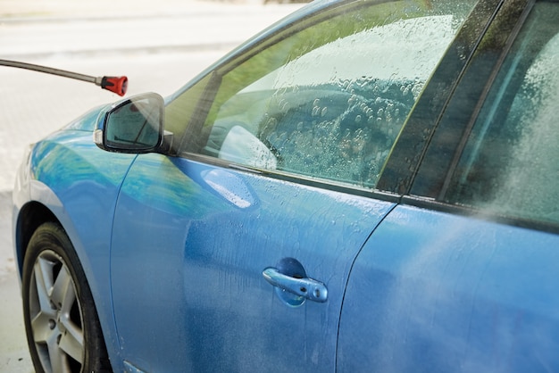 Cleaning car with high pressure water at car wash station